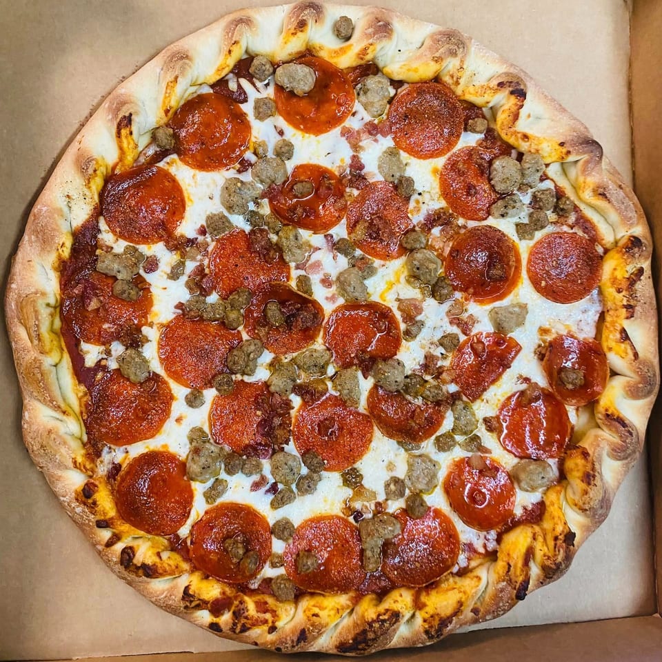 A DAIQUIRIS & DEAUX PIZZA pepperoni and sausage pizza with a braided crust in a box.